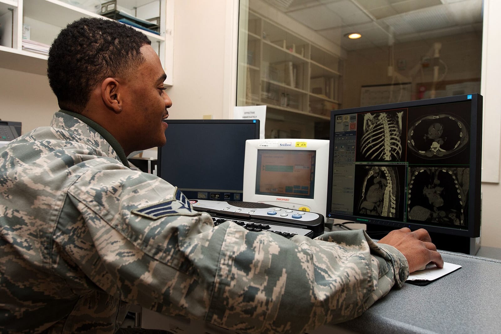 A diagnostic imaging technician reviewing CT scans on a hospital workstation