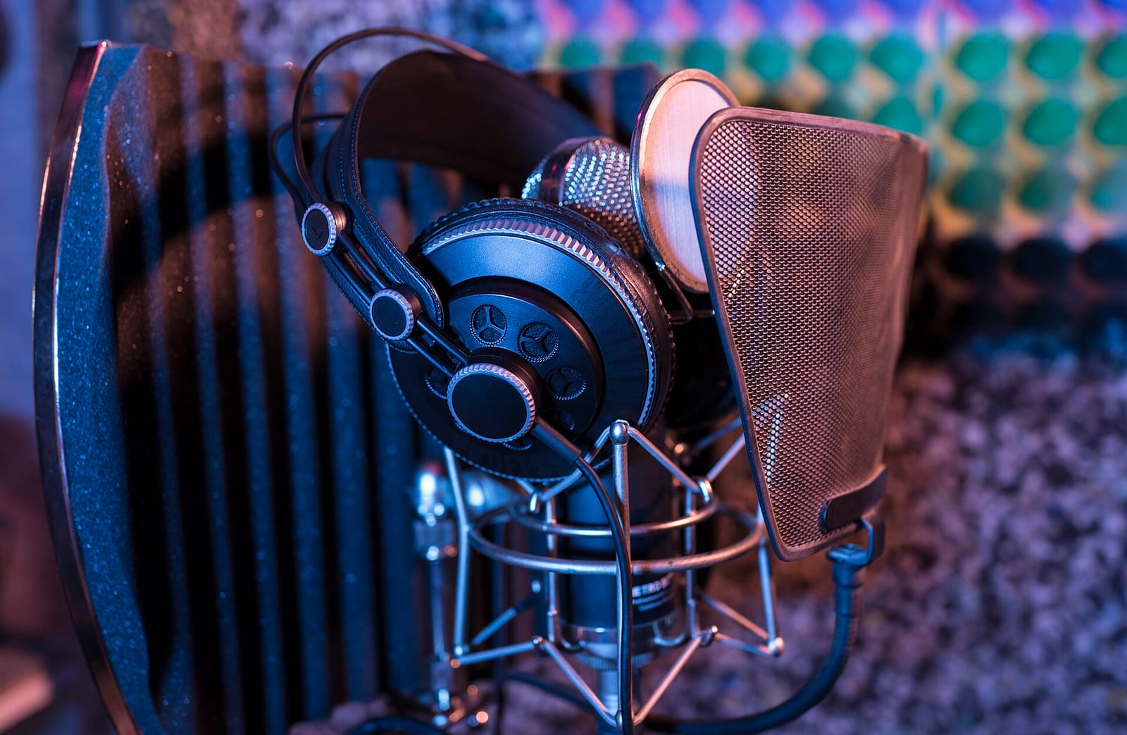 Studio headphones hanging on a condenser microphone with a pop filter in a recording booth