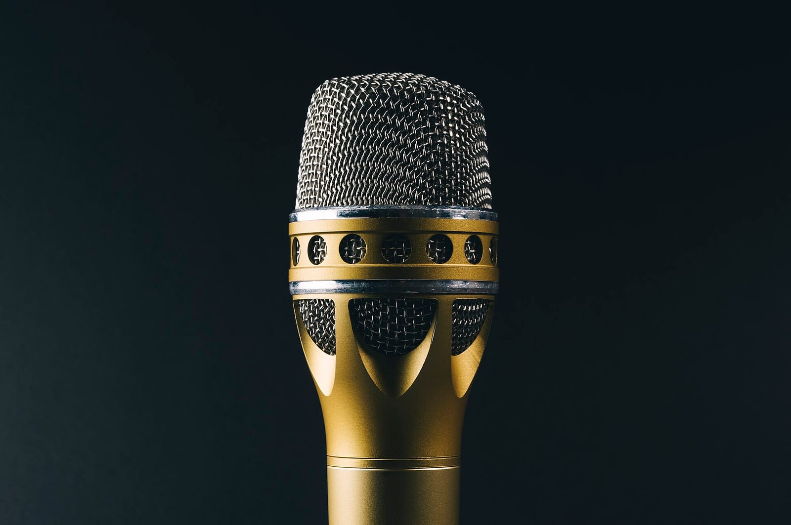 A gold and silver handheld microphone against a dark background