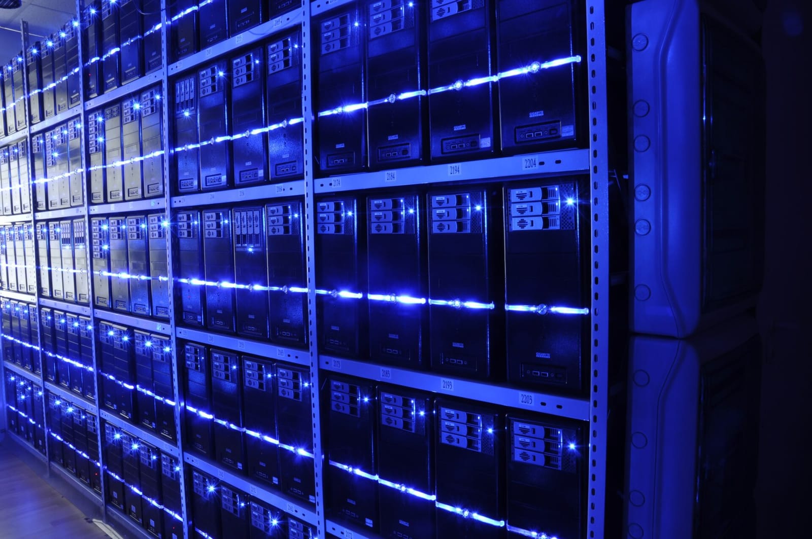 Rows of server racks lit in blue inside a data center hall