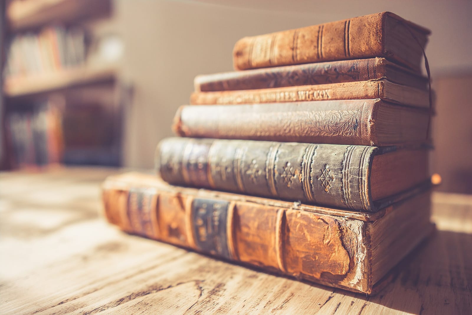 A stack of old leather-bound books on a wooden table