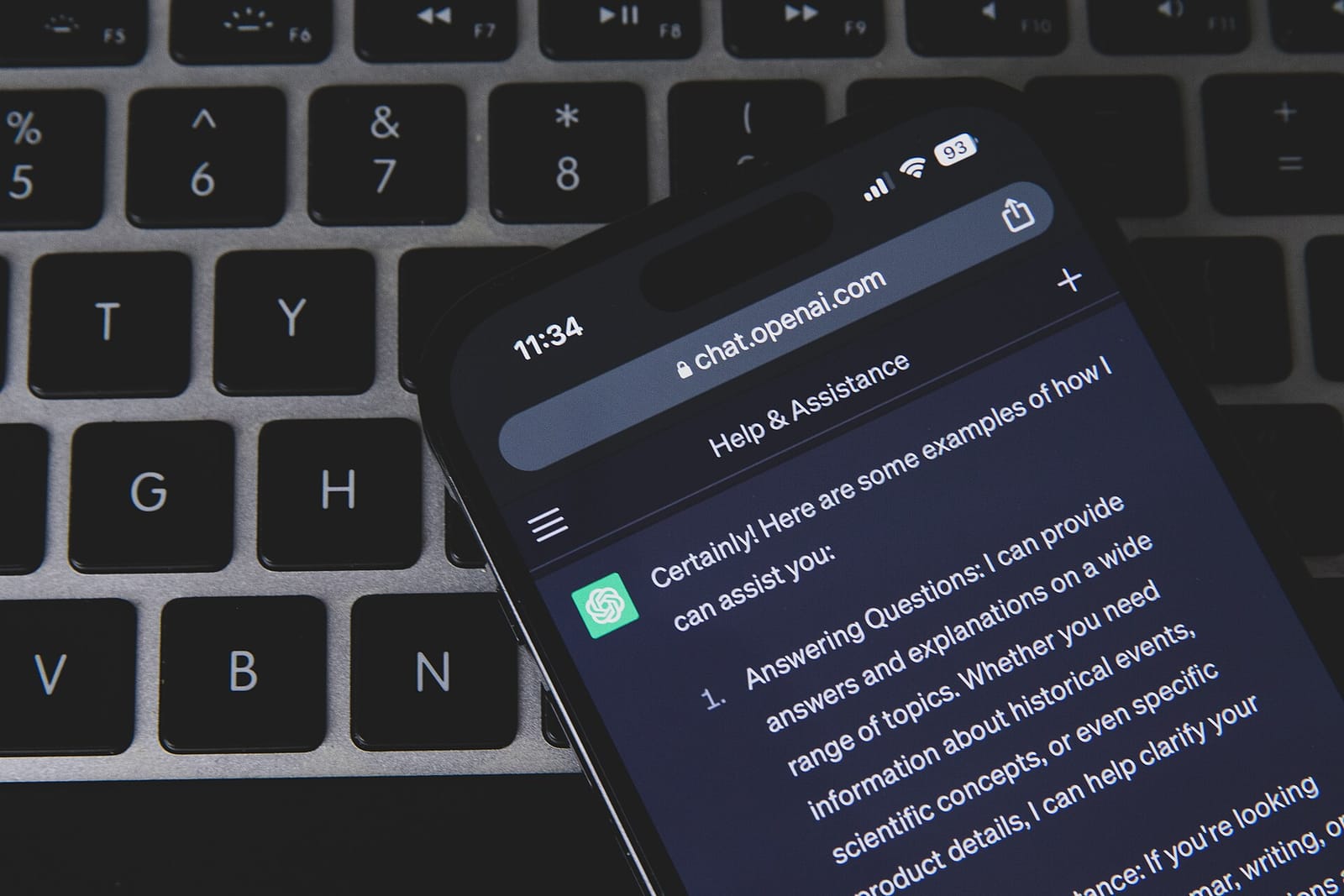 A smartphone showing a ChatGPT answer, lying on a laptop keyboard