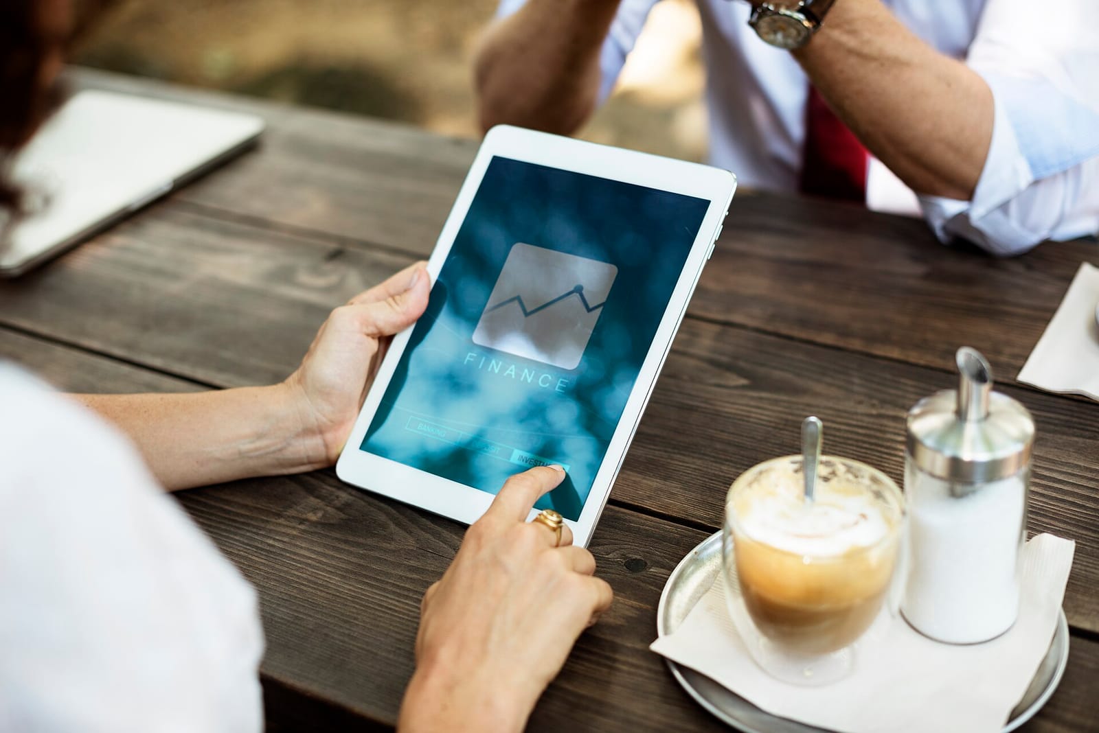 Hands holding a tablet showing a line chart at a café table
