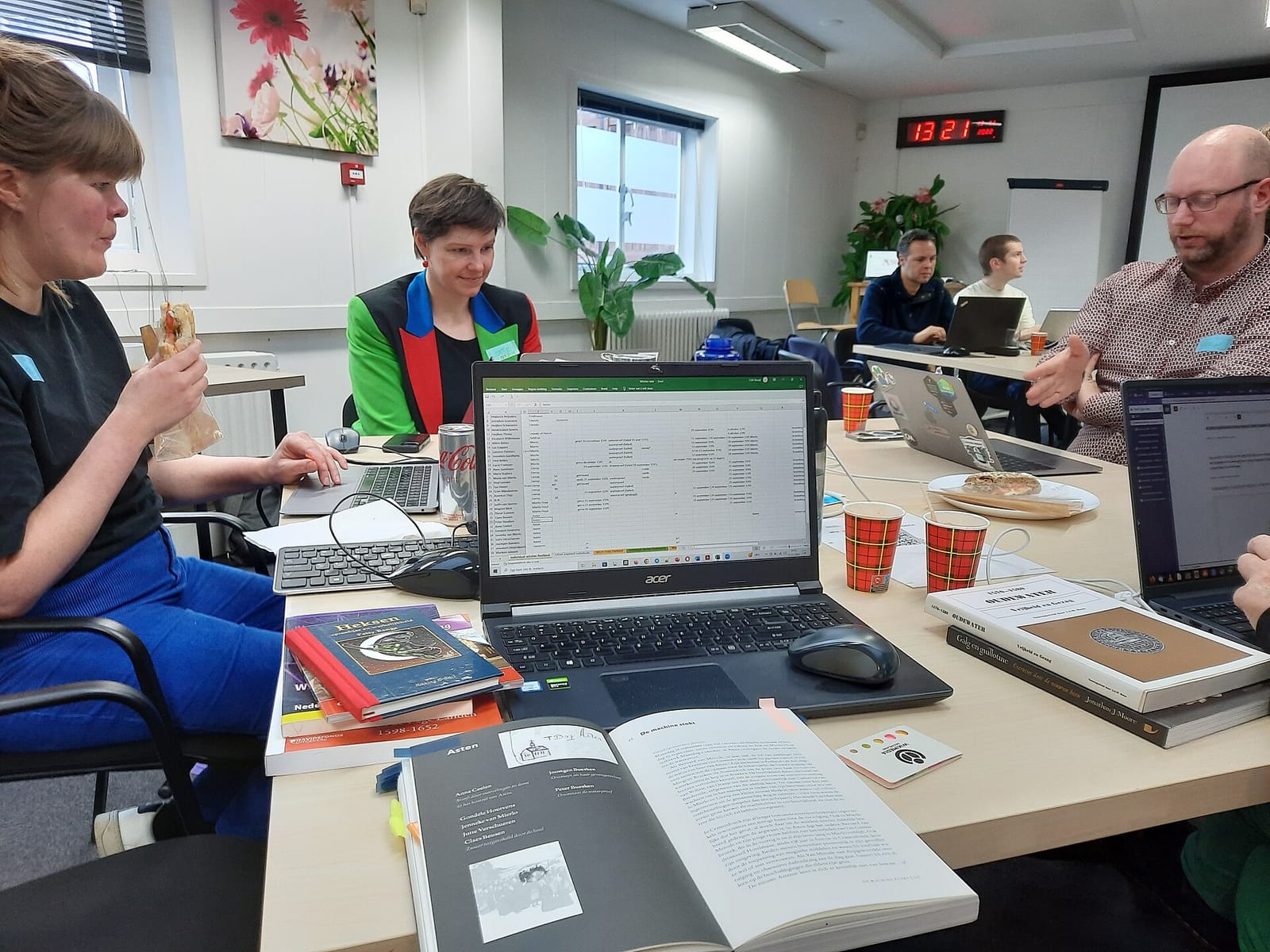 People working together on laptops around a table at a community hackathon