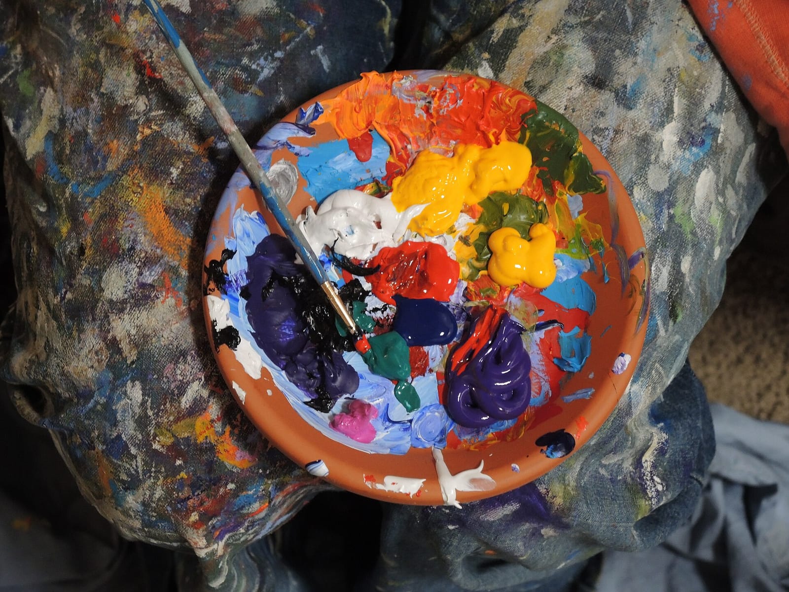 A painter's palette dish full of mixed acrylic colours with a brush