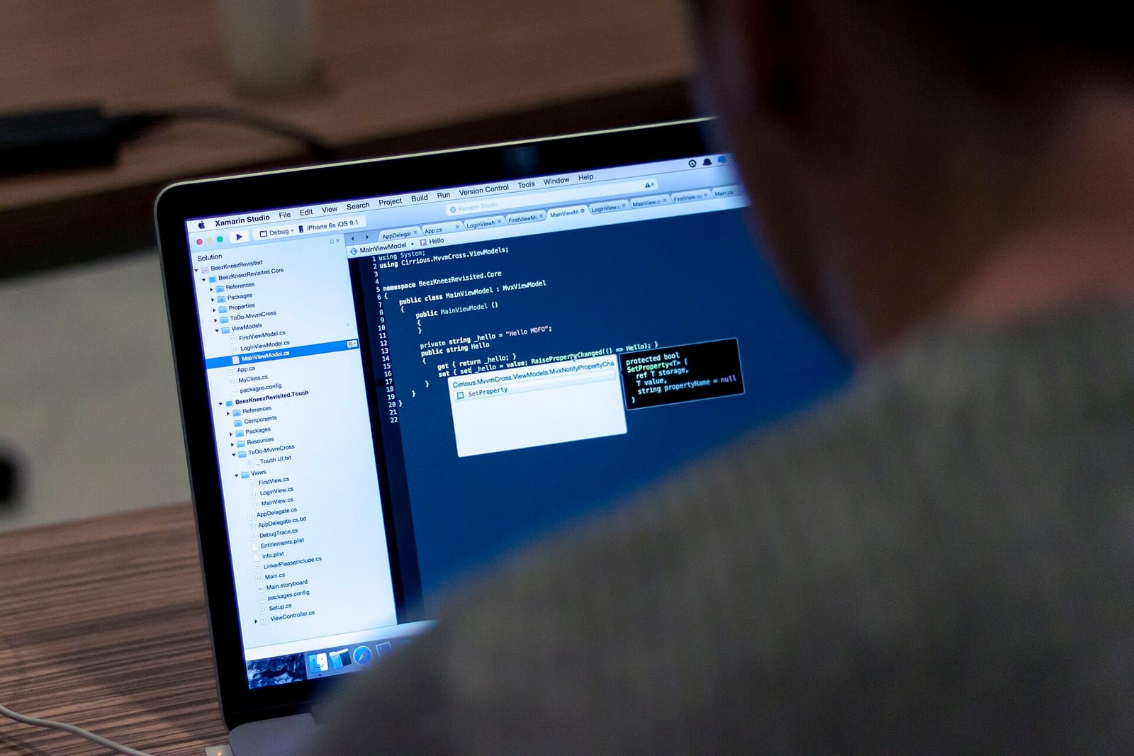 A developer seen from behind writing code on a laptop