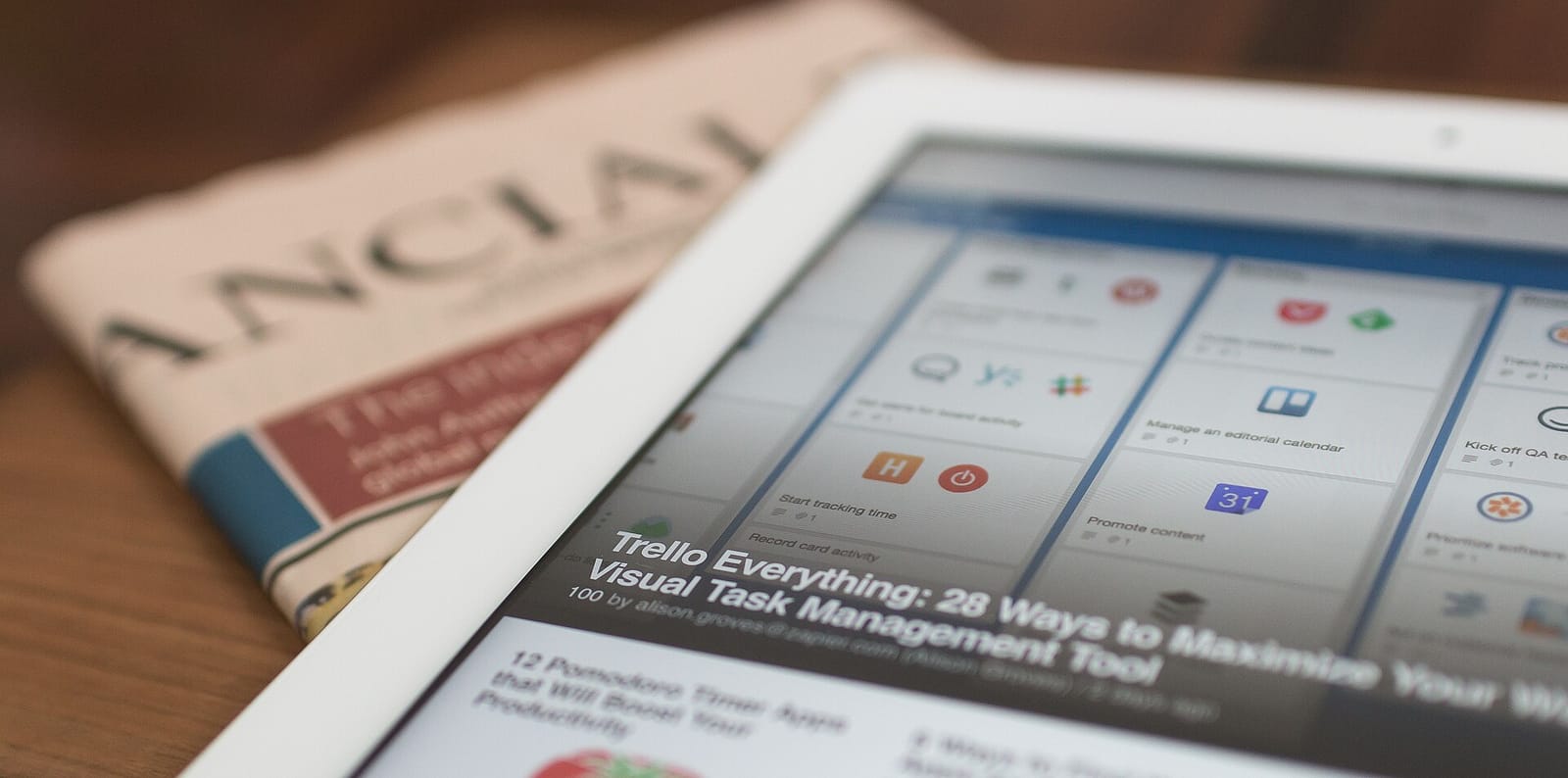 A tablet showing news articles lying on a printed newspaper