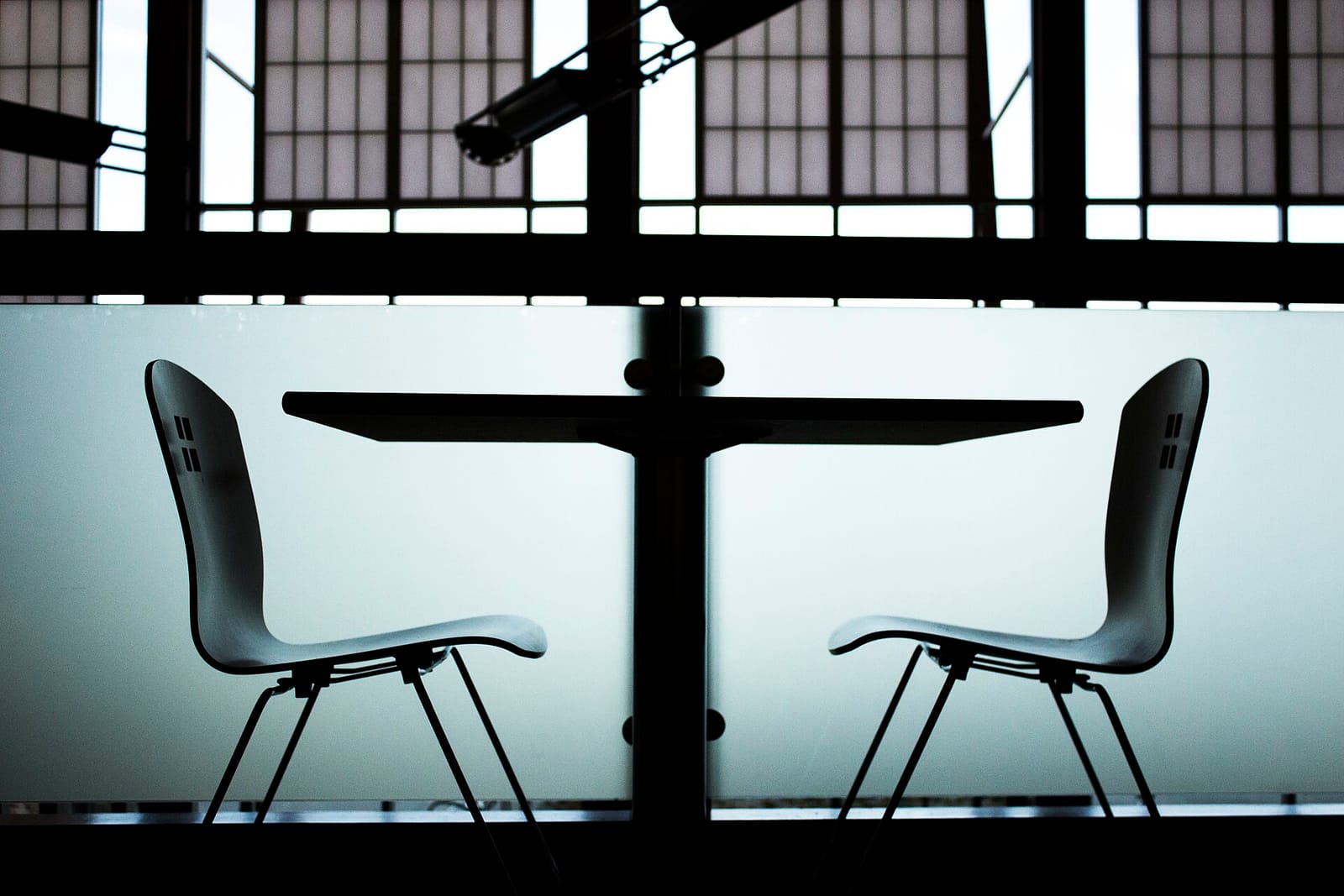 Two empty chairs facing each other across a small table in silhouette
