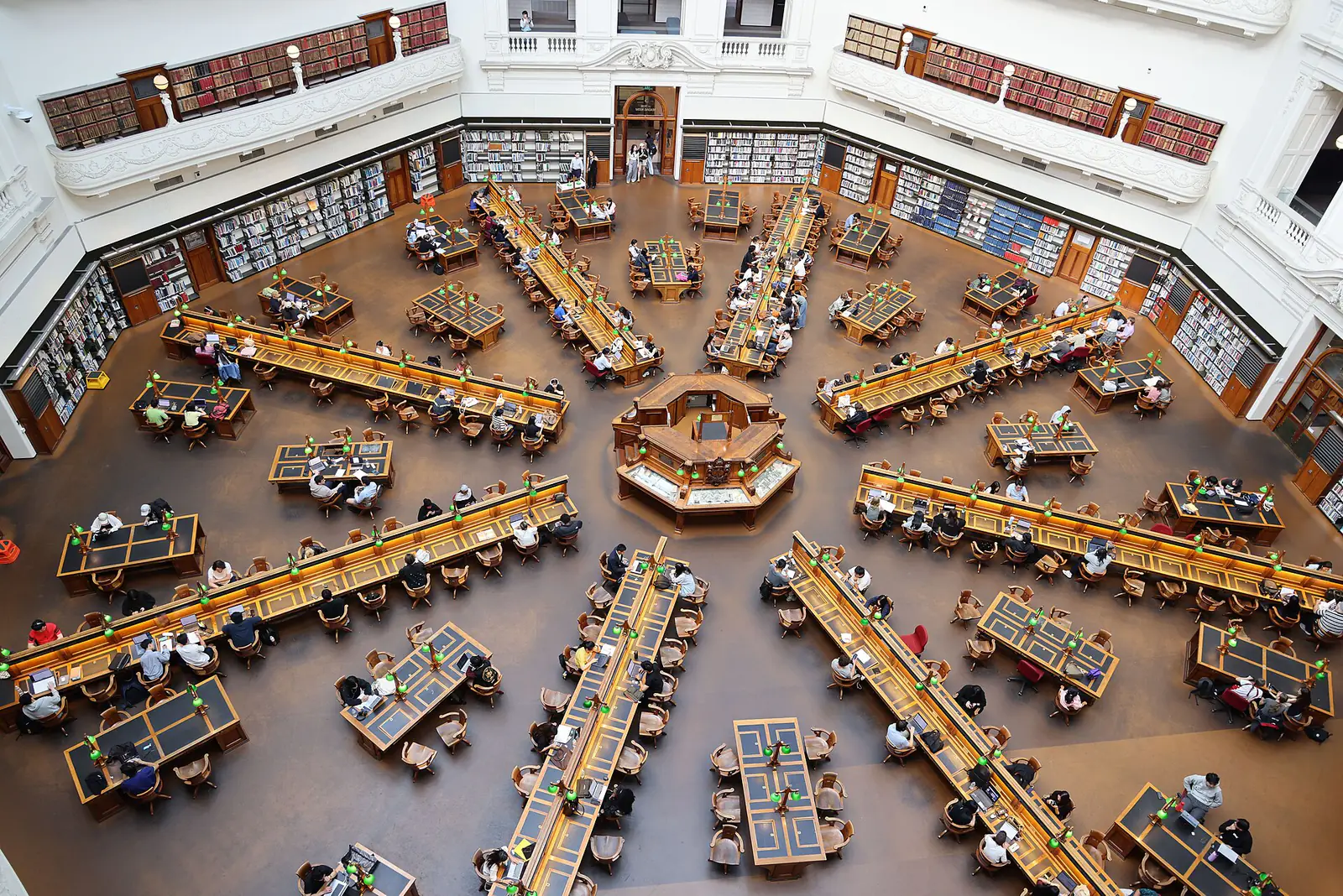 Aerial view of a domed library reading room with long desks radiating from a central counter