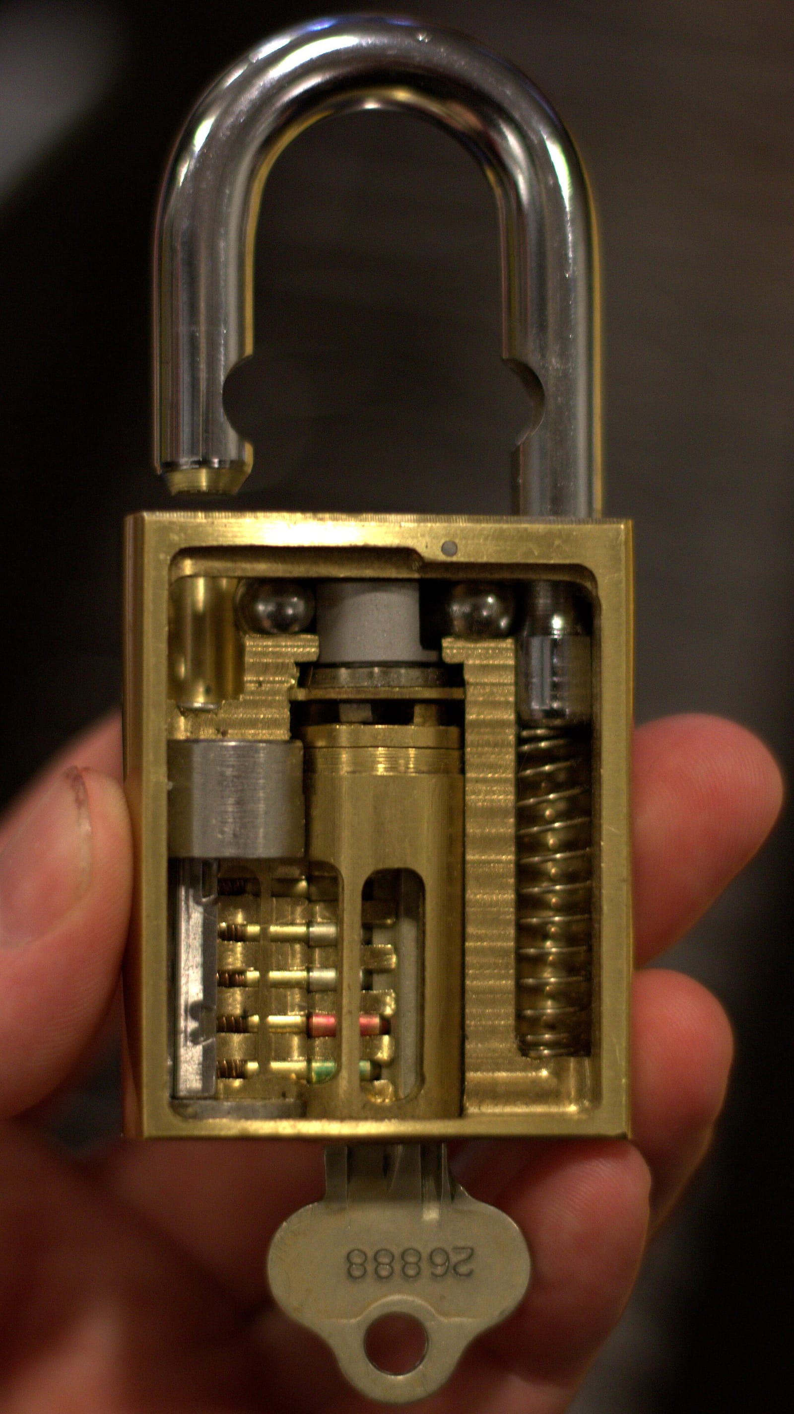 A cutaway padlock held in a hand, showing its internal locking mechanism