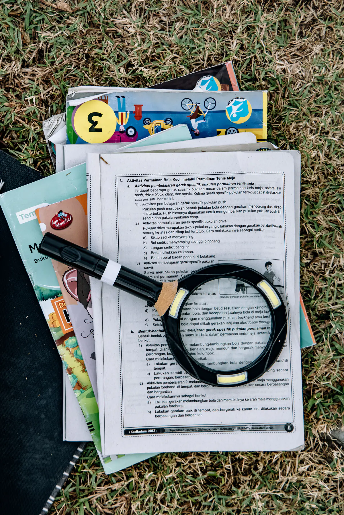 A magnifying glass resting on top of books and papers