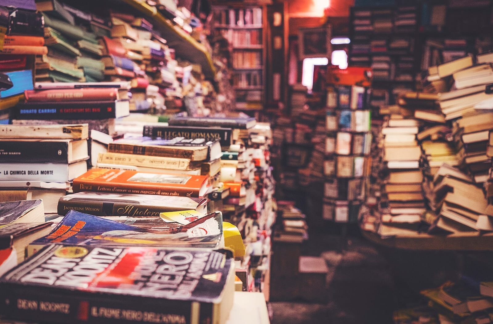 Towering piles of books filling a crowded bookshop