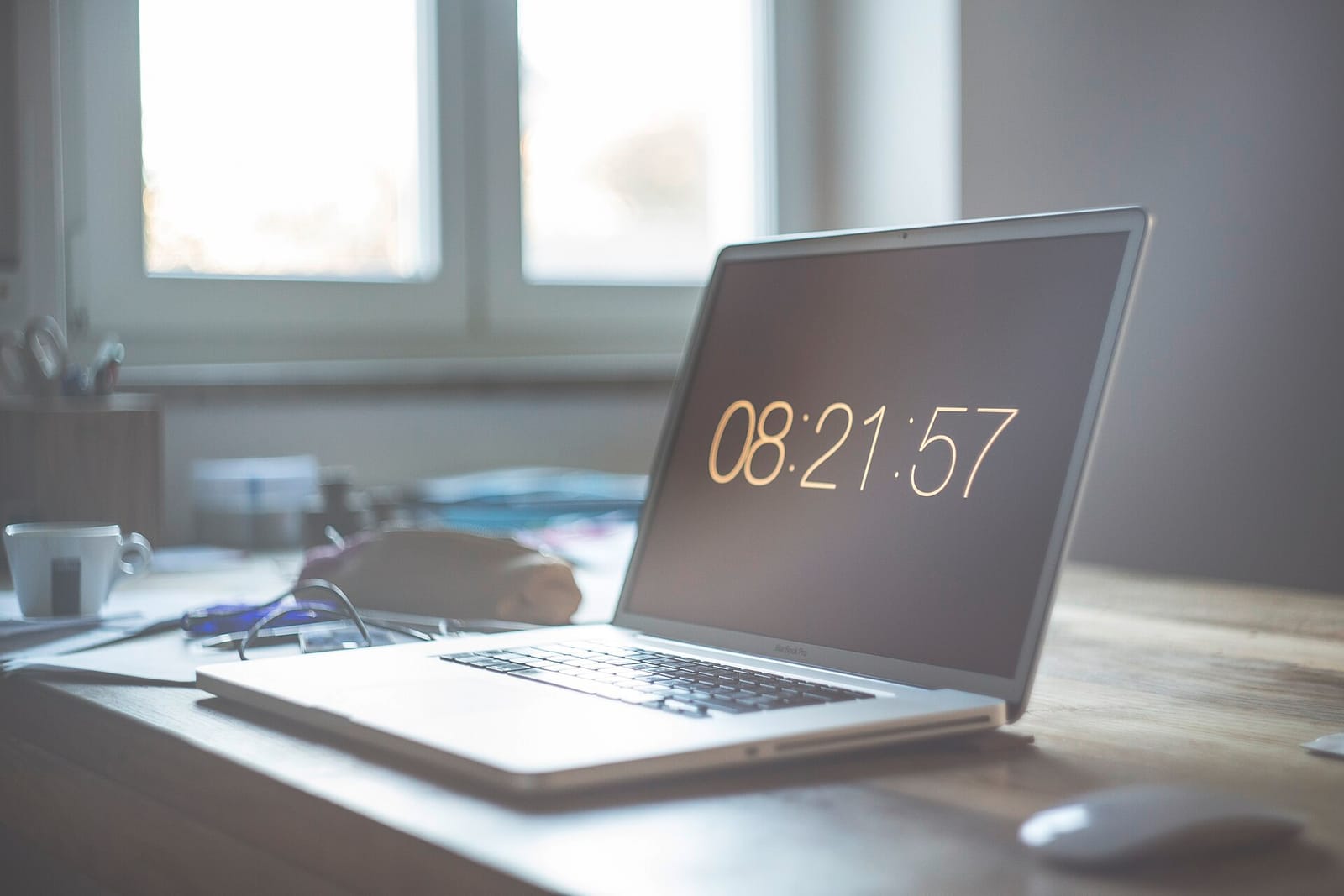 A laptop on a wooden desk by a window