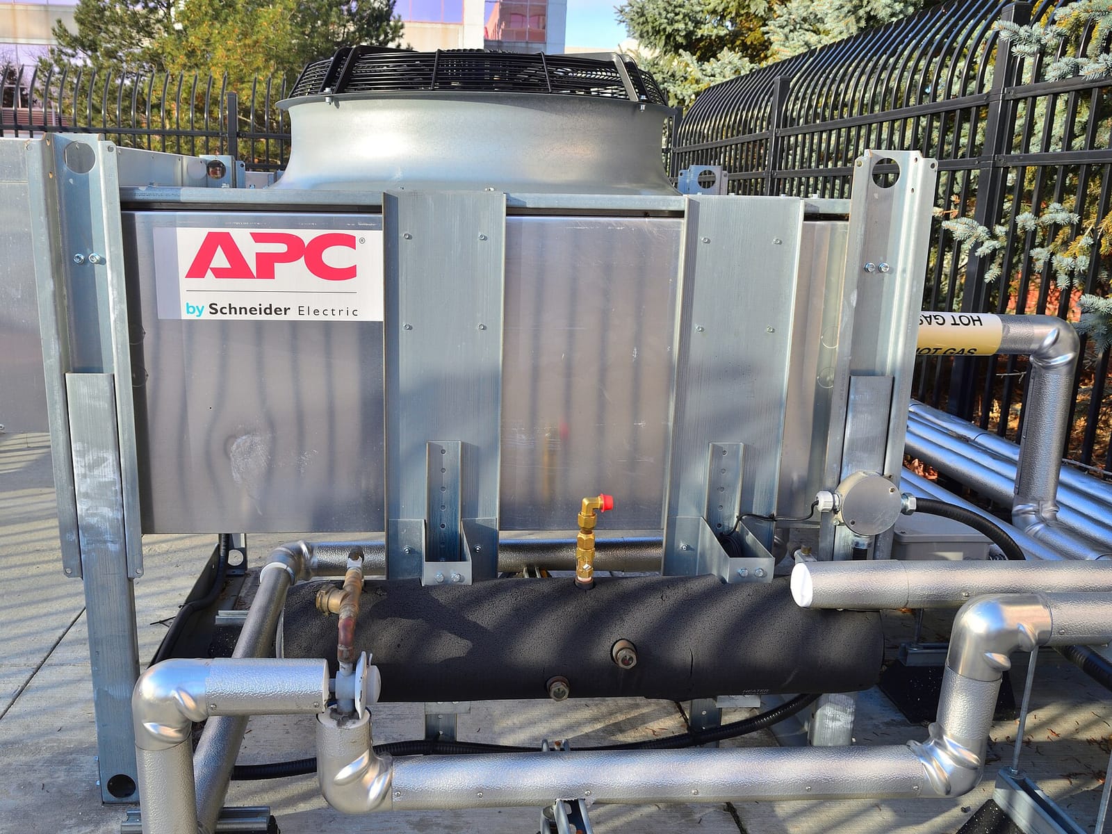 An outdoor APC data center cooling unit with fan housing and insulated pipes