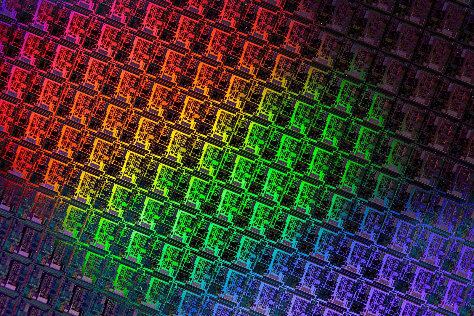 Close-up of a patterned silicon wafer reflecting rainbow colours across its chips