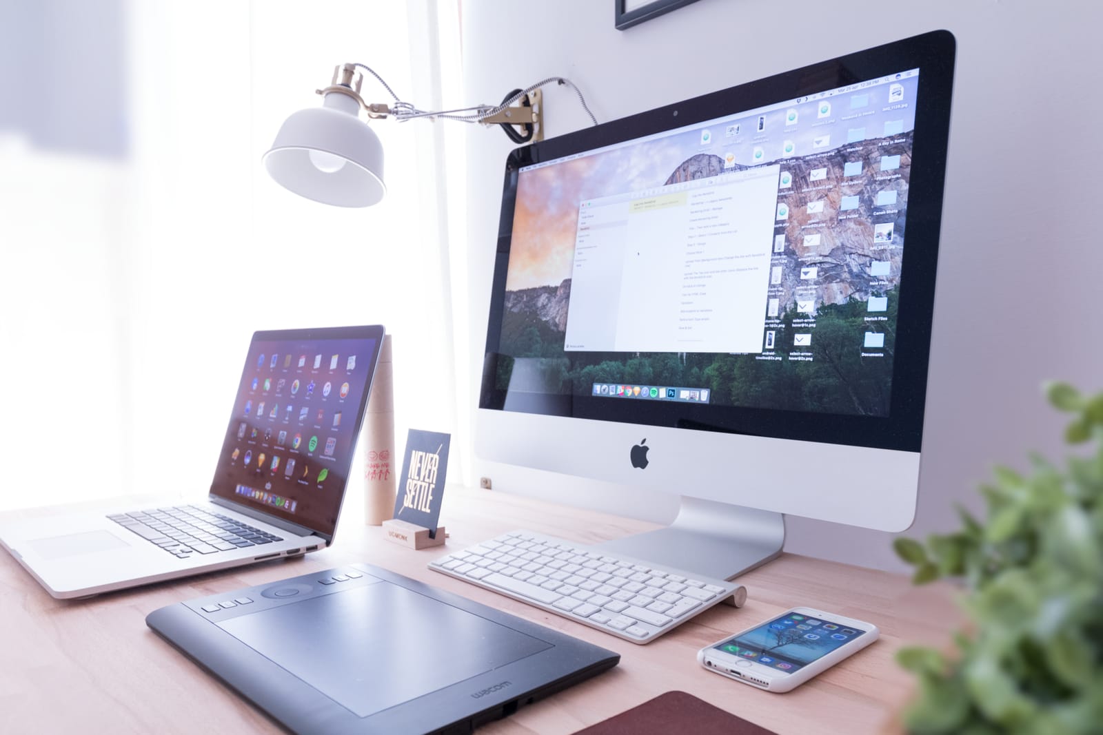 Desk with an iMac, a laptop, a drawing tablet and a smartphone