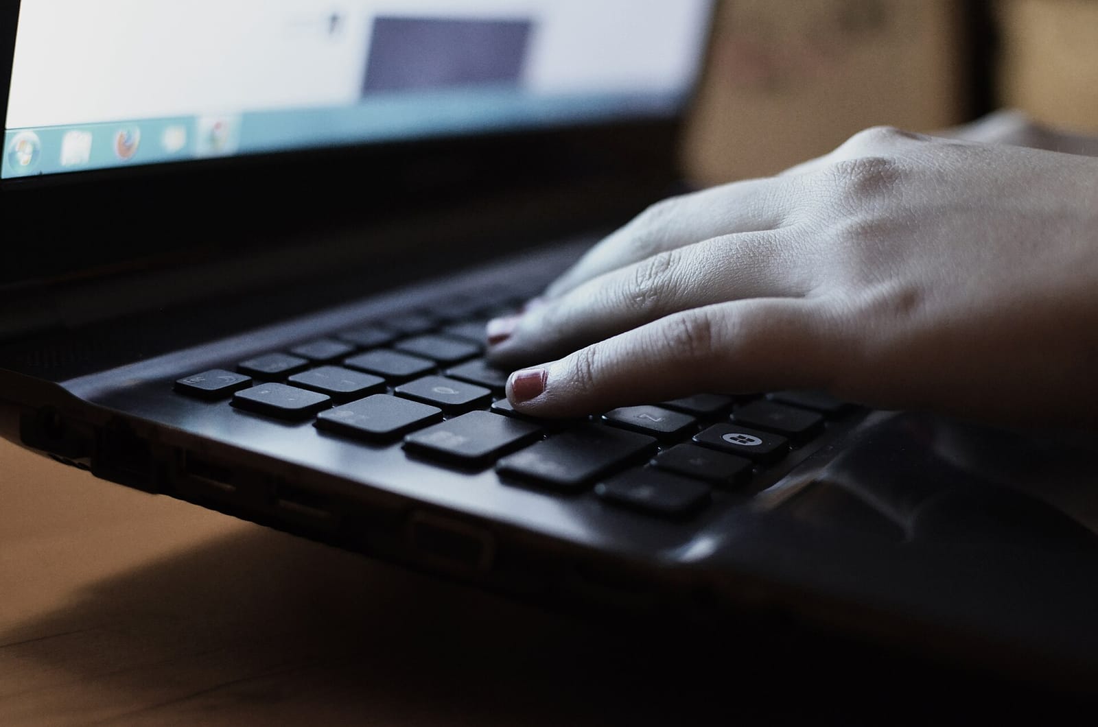 Close-up of a hand typing on a laptop keyboard