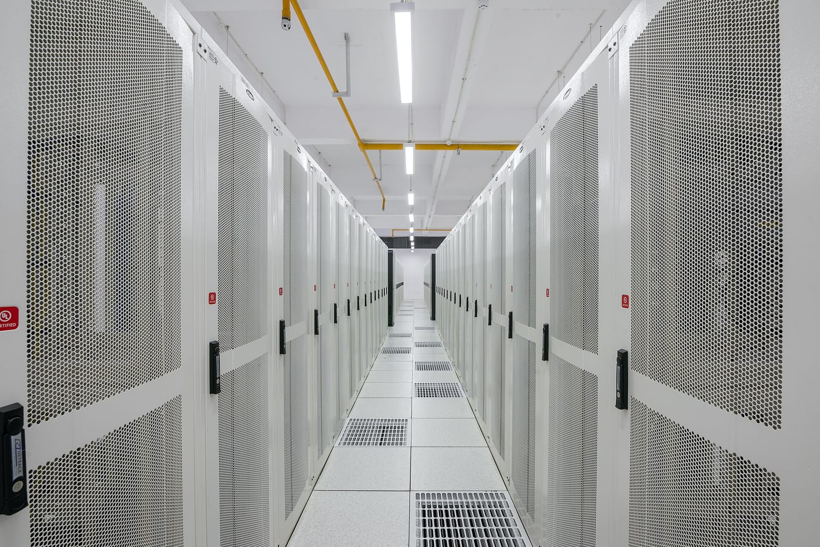 Long aisle between rows of white server racks in a data center