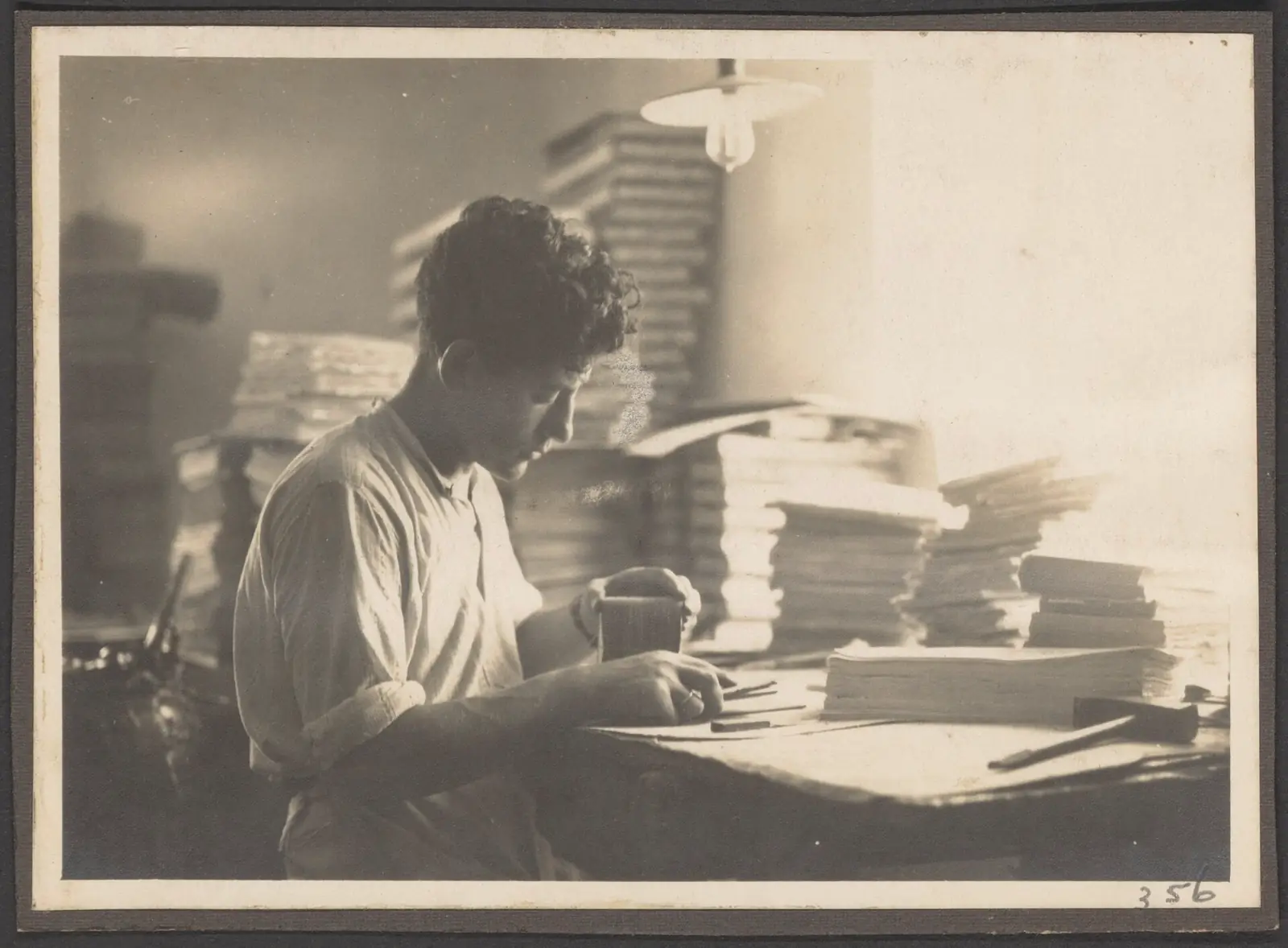 A man working behind a desk piled high with stacks of paper