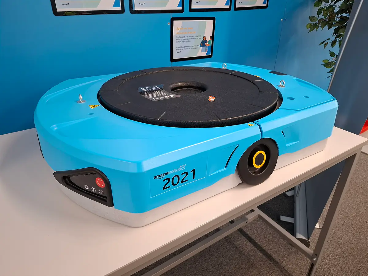 A low, round blue Amazon drive unit robot on display at a fulfilment centre