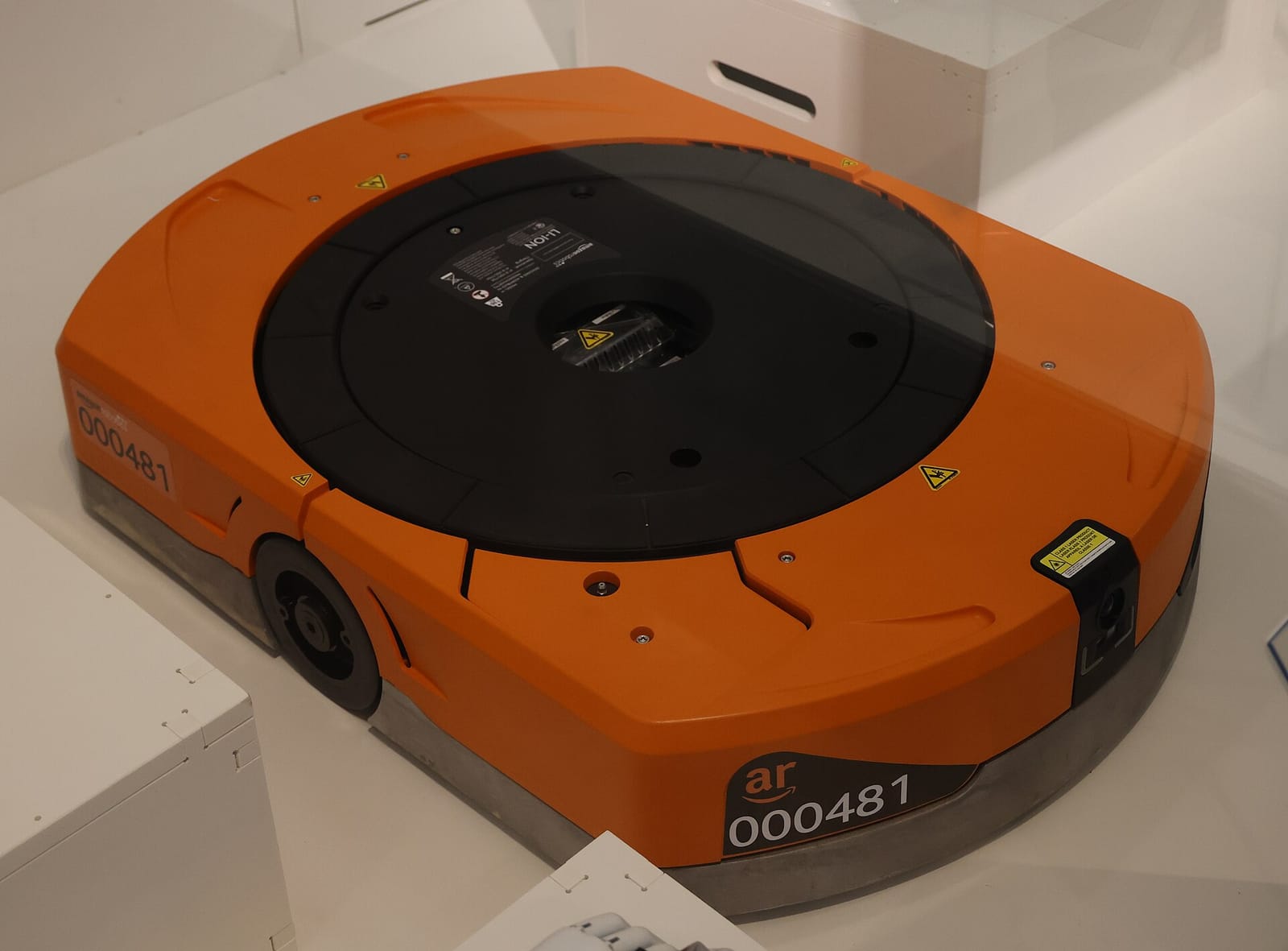 An orange Amazon drive robot on the floor of an Amazon warehouse