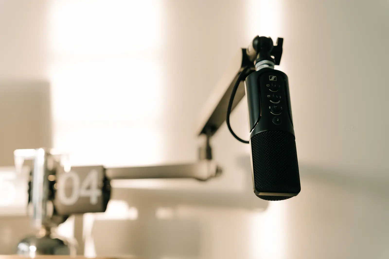 A professional microphone on a boom arm in a minimal studio