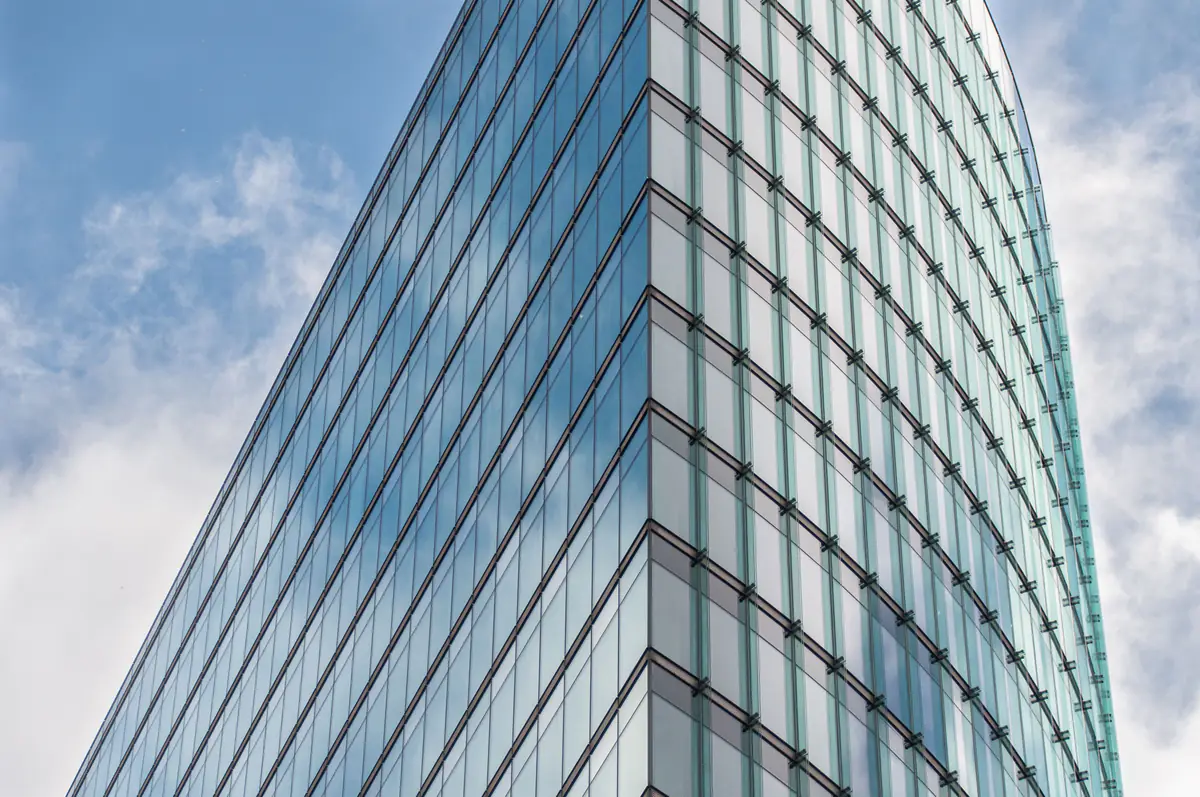A glass office skyscraper reflecting a blue sky