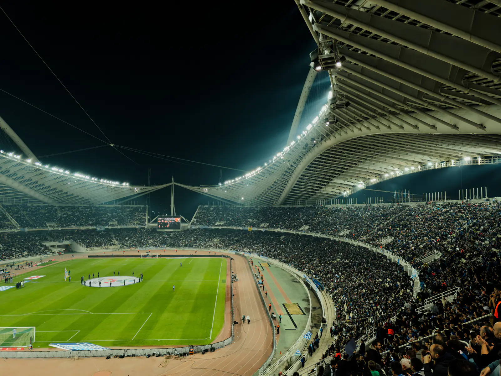 A crowded soccer stadium lit by floodlights at night
