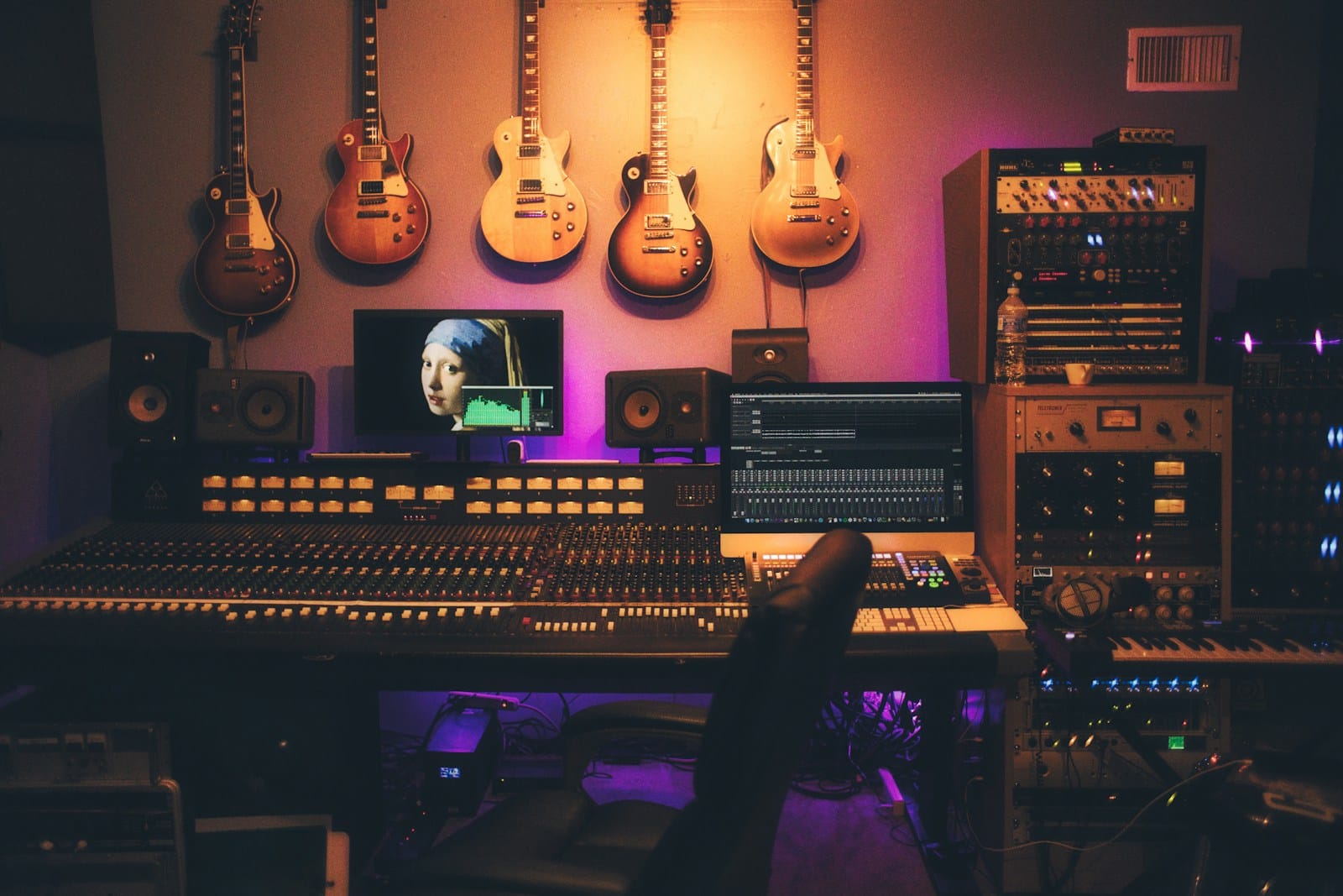Music recording studio with guitars on the wall and a large mixing console